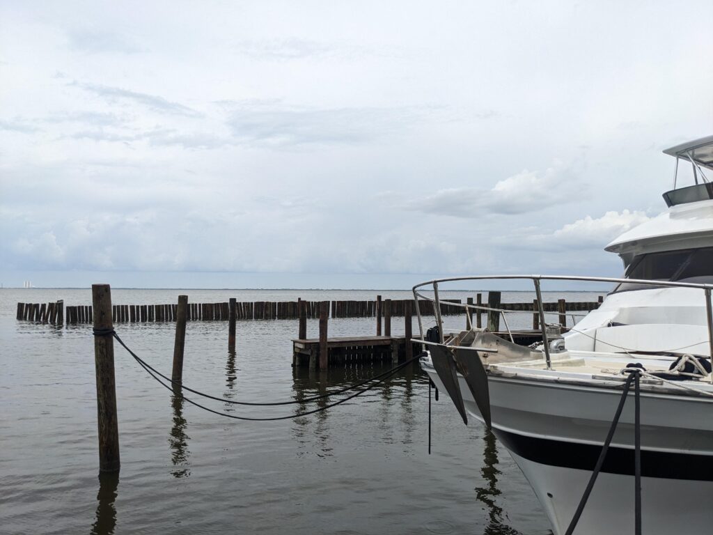 Docks with a boat tied up to the right. In the distant left is the Vehicle Assembly Building