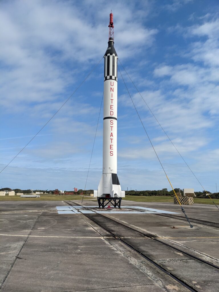 A black and white Mercury Redstone rocket sitting on a concrete launch pad.